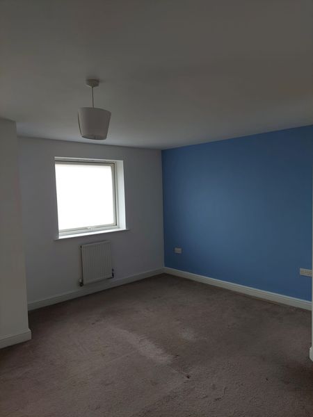 Bedroom repainted in white with a blue feature wall