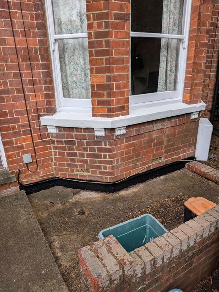 Exterior of a brick house with freshly painted white bay window frames and sills