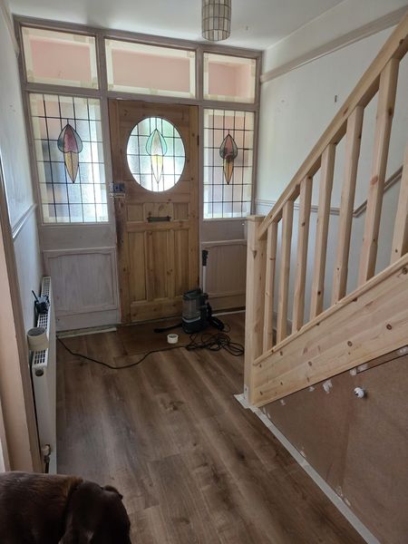 Before: hallway with an unpainted pine staircase beside the stained-glass front door