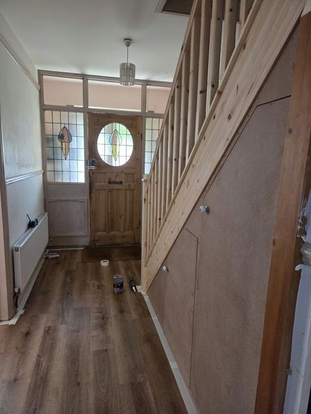 Before: hallway and staircase with bare pine spindles and unpainted under-stairs panelling