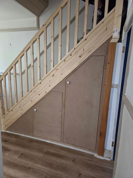 Before: bare pine staircase and under-stairs panels ready for painting