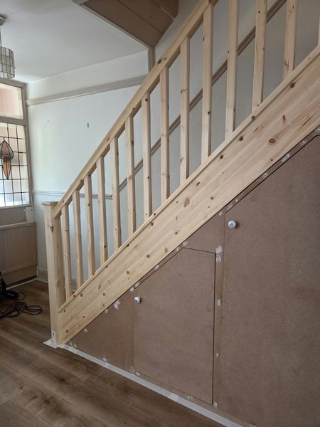 Before: unpainted staircase spindles and under-stairs cupboard panels