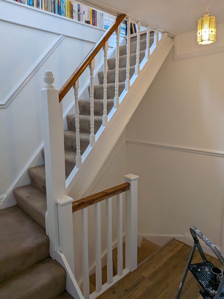 Staircase after decorating, with white spindles and newel posts and a varnished oak handrail