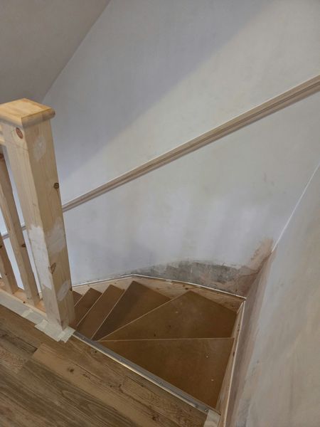 Before: view down bare wooden stairs from the landing