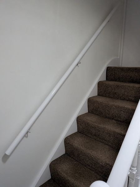 Carpeted stairs with a newly painted wall-mounted handrail