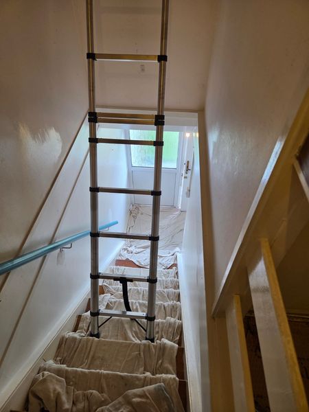 In progress: stairwell being prepared, with a ladder and dust sheets on the stairs